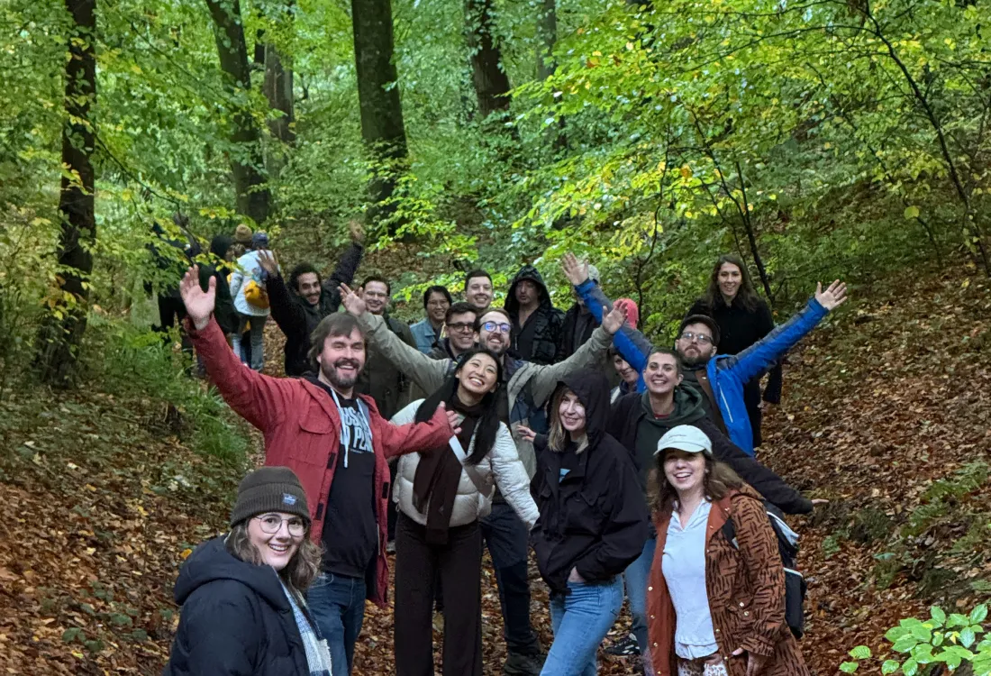 A group of hikers pose, arms raised in celebration, in the woods outside of Bristol, UK on their way to see a small grove of Redwood trees.